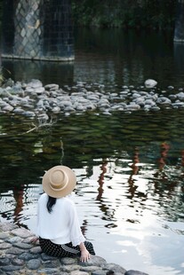 湖畔戴帽女子静赏水景