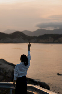 夕阳下一人海边高举手臂