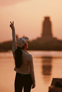 夕阳下女子抬手望向远方