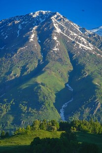壮丽雪山下的翠绿山峦