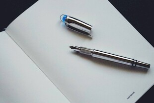 精致钢笔置于翻开笔记本上