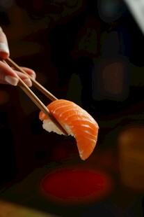 筷子夹起的美味三文鱼寿司