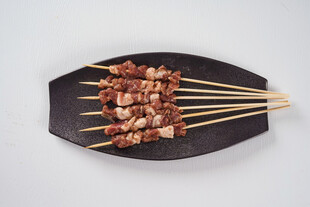 美味烤肉串摆于黑色盘上