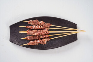 美味羊肉串摆于黑色盘上