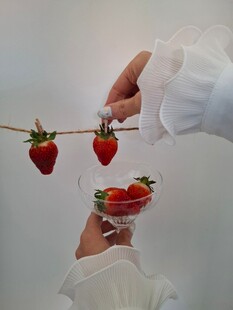 手悬草莓于酒杯上方