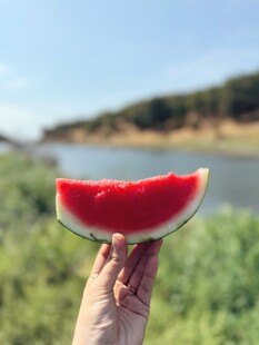 手举鲜切西瓜赏湖景