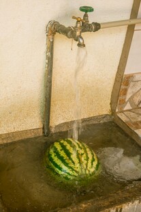 水龙头下冲洗的新鲜西瓜