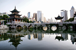 中式古桥映于城市湖景中