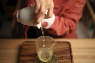 手倾茶壶倒出金黄茶汤