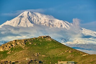 壮丽雪山下的绿色山丘
