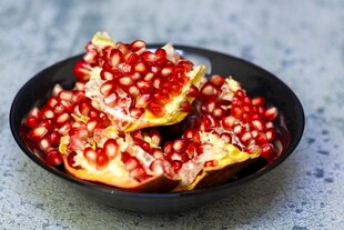 黑碗中的新鲜红石榴果肉
