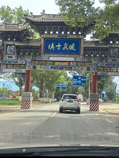 暖泉古镇牌坊前的行驶车辆
