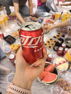 手持可乐置身丰盛美食中