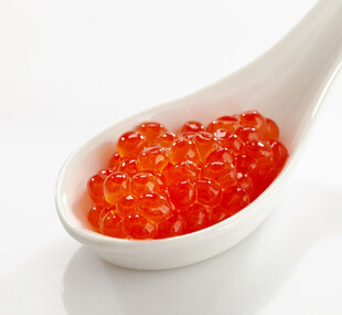 白色小勺中的鲜红鱼子酱