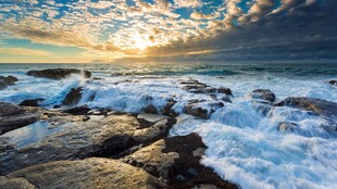 海边日出海浪拍打礁石