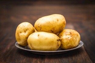 木桌上盘子里的新鲜土豆