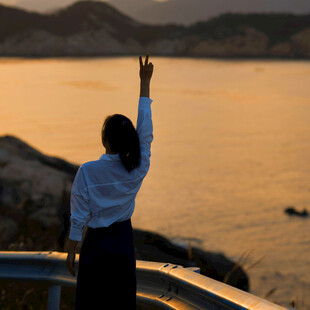 女子海边逆光高举手臂