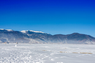 广阔盐湖与远处雪山美景