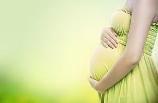 孕妇身着绿裙轻抚孕肚