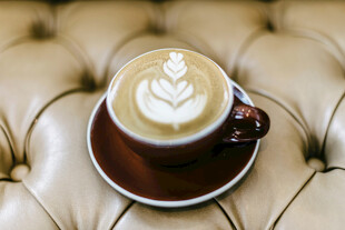 精致拉花咖啡置于皮沙发上