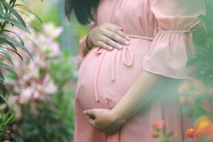 孕妇于花丛中轻抚隆起腹部