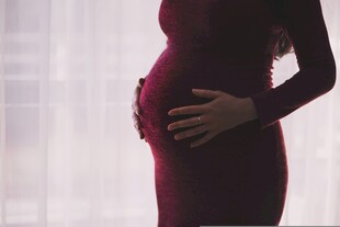 孕妇身着红衣轻抚隆起腹部