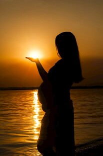 夕阳下的孕妇海边温柔剪影