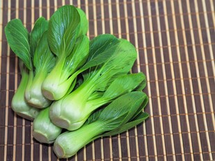 新鲜青菜摆放在竹席上