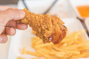 手拿美味炸鸡腿与薯条
